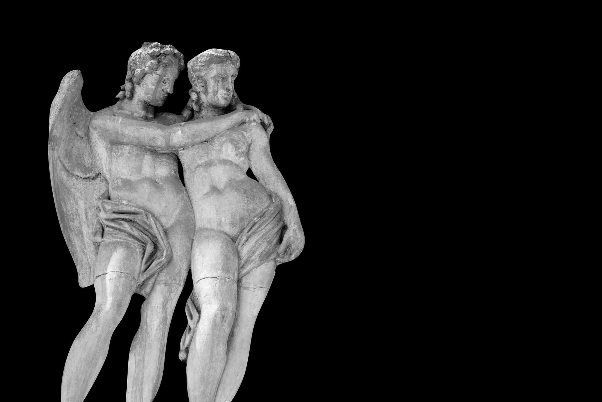 Cupid and Psyche. An ancient stone statue on black background. Copy space.